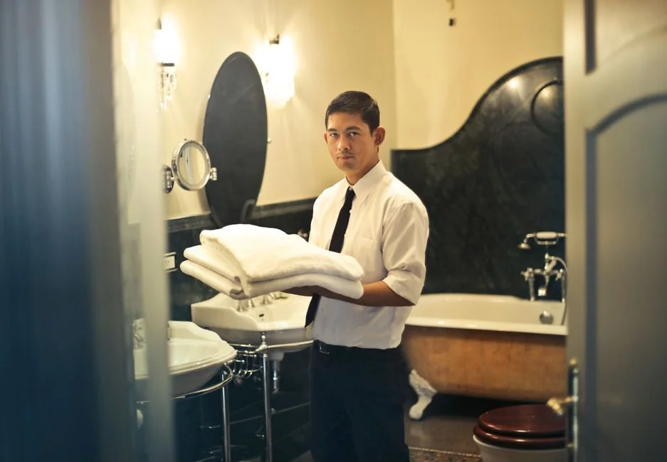 Un homme nettoie une porte vitrée à l’intérieur à l’aide d’un vaporisateur et d’un chiffon.